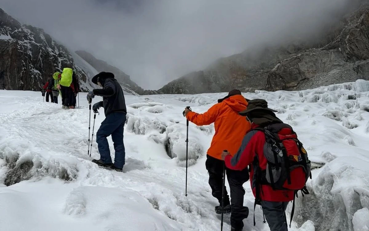 Group of trekkers with guide crossing glacier terrain in Nepal Himalayas during guided mountain expedition