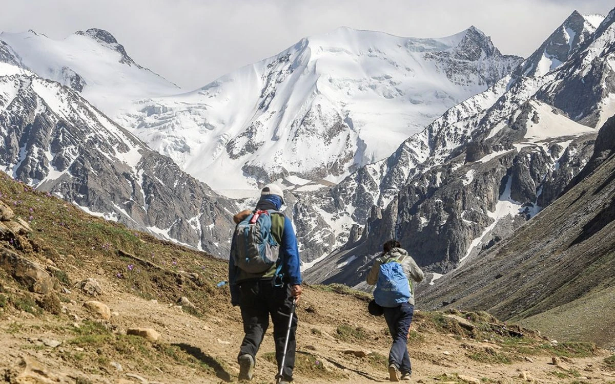 Two hikers trekking toward snow-capped peaks in Nepal Himalayas