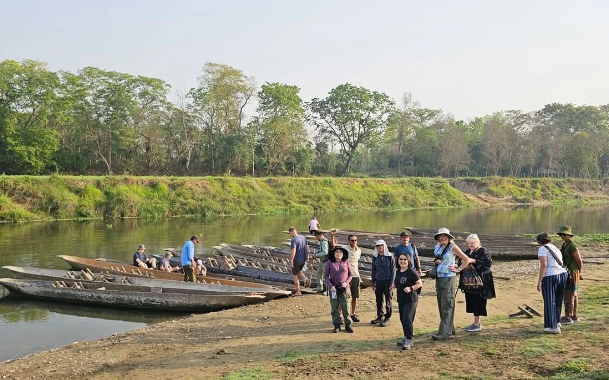 Tourist group with guide standing by traditional wooden canoes on jungle riverbank