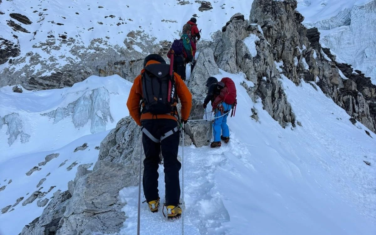 Roped climbers navigating a rocky ridge on Island Peak