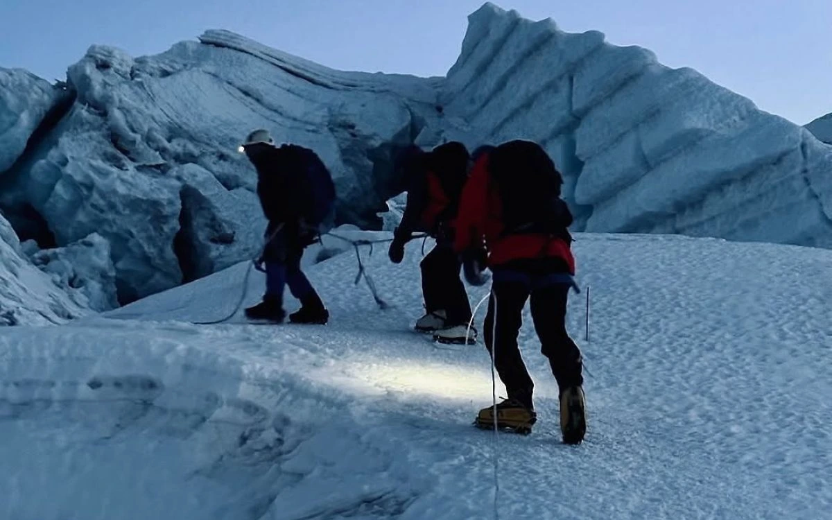 Climbers crossing an icy ridge before dawn on Island Peak