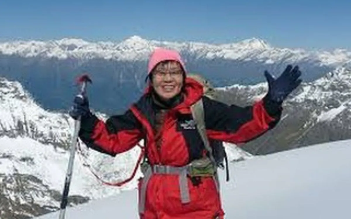 Junko Tabei celebrating on a snowy mountain peak in red climbing gear