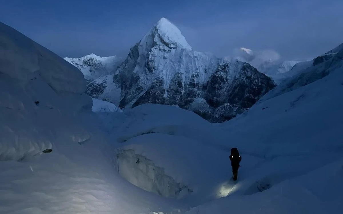 Headlamp-lit climber crossing the Khumbu Icefall in the dark early morning hours