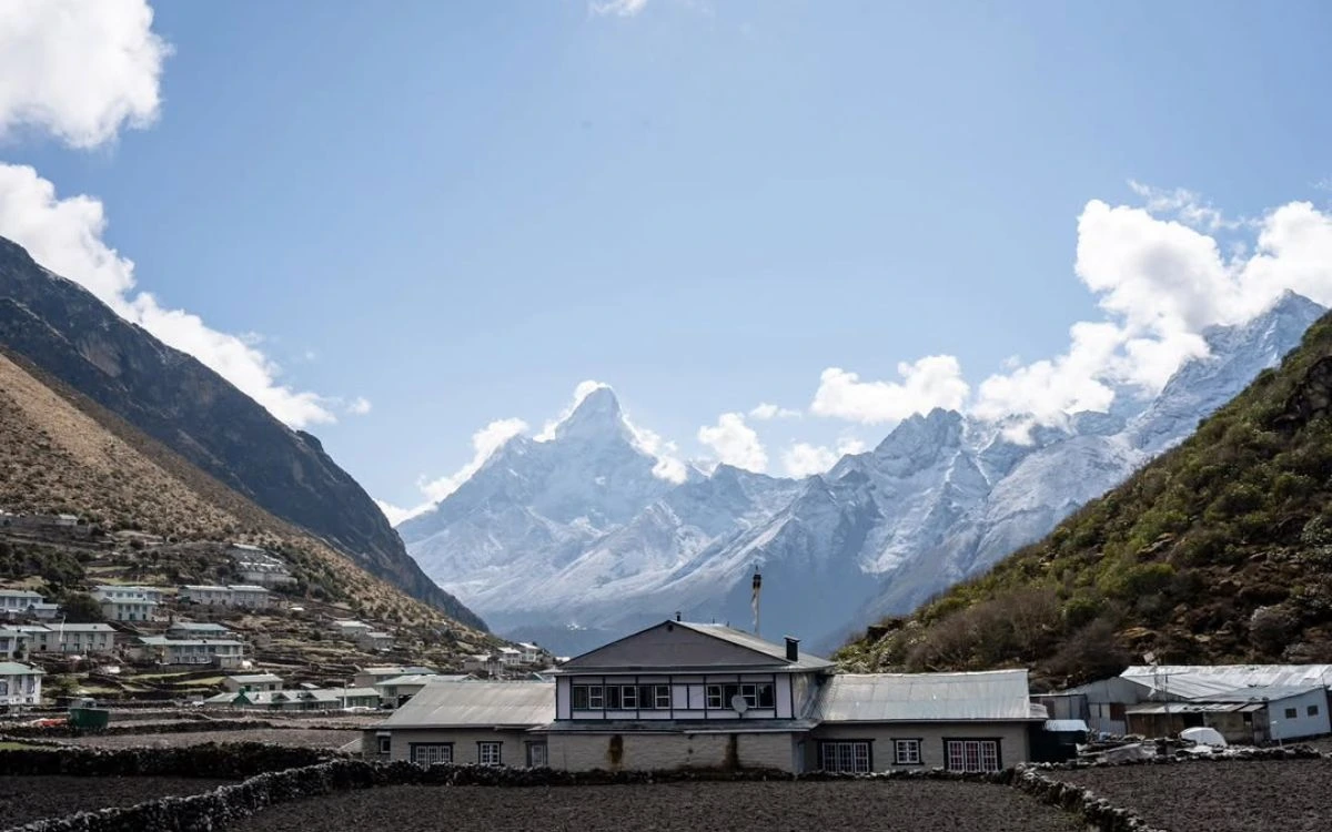 Khumjung village school building with Ama Dablam's distinctive peak rising sharply between valley walls in the background