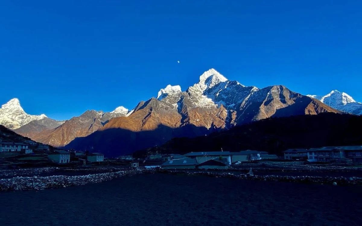 Early morning panorama of Khumjung village with moonlit snow-capped Himalayan peaks glowing above the quiet settlement