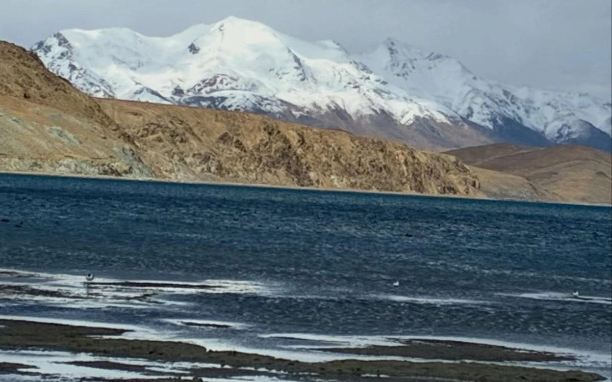 Snow-capped peak overlooking the dark waters of Lake Manasarovar
