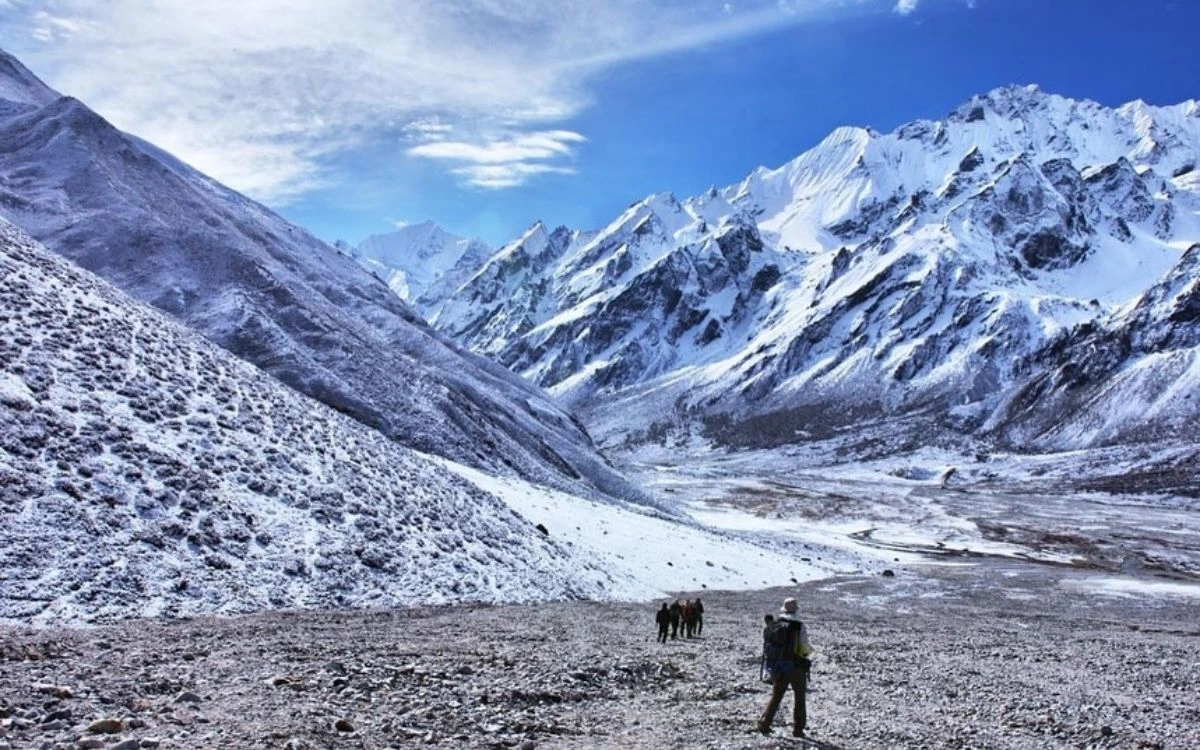 Trekkers walking through snow-covered Langtang Valley with Himalayan peaks in background