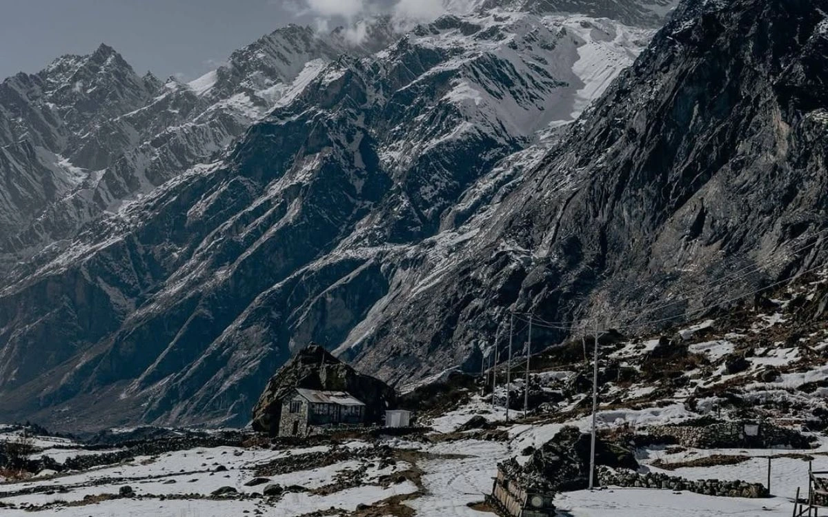  Stone teahouse with prayer flags against dramatic mountain backdrop in Langtang region