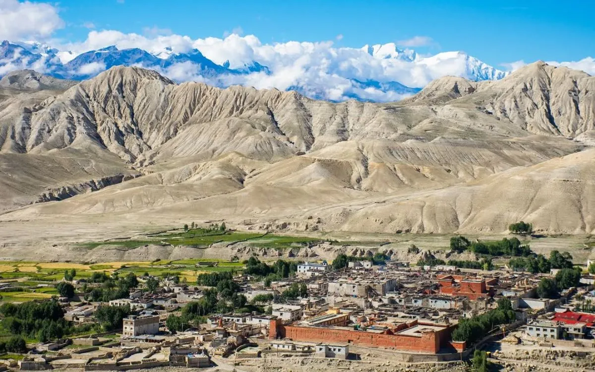 Lo Manthang settlement nestled in Upper Mustang's desert landscape with colorful buildings and mountain backdrop