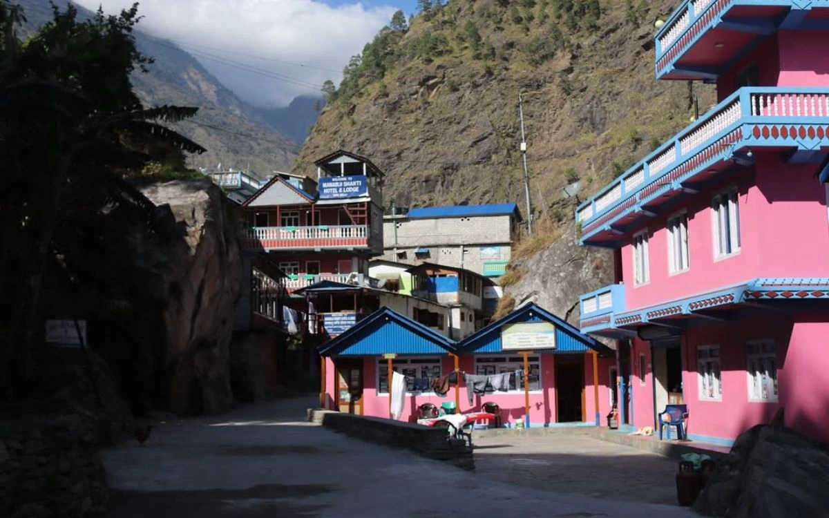 Colorful teahouses and lodges in Machha Khola village with mountain backdrop