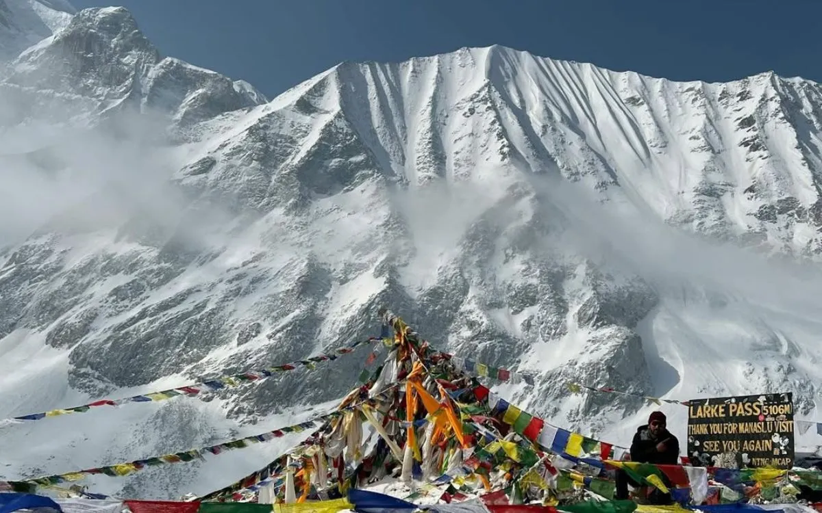 Larke Pass summit at 5106m with colorful prayer flags and dramatic mountain backdrop on Manaslu Circuit trekking route