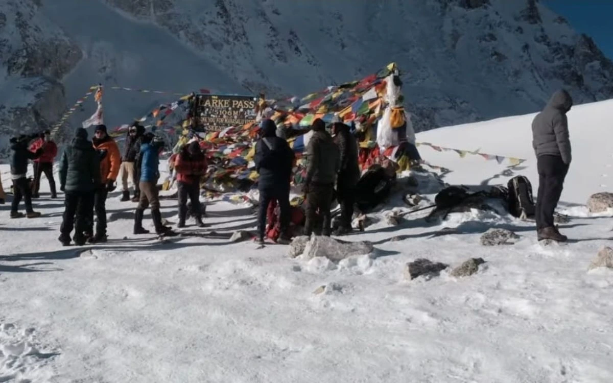 Trekkers celebrating at Larkya La Pass summit with prayer flags