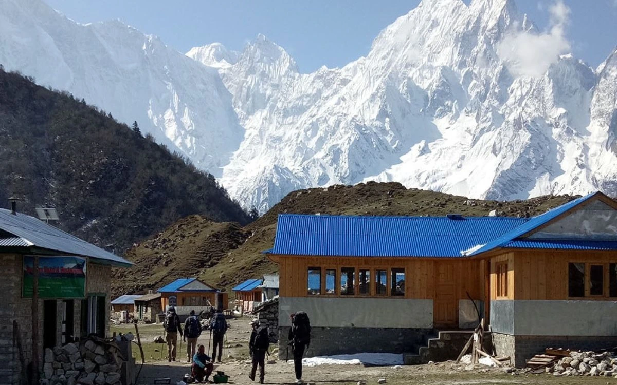 Teahouse lodges with blue roofs beneath snow-capped Himalayan peaks on the Manaslu Circuit Trek