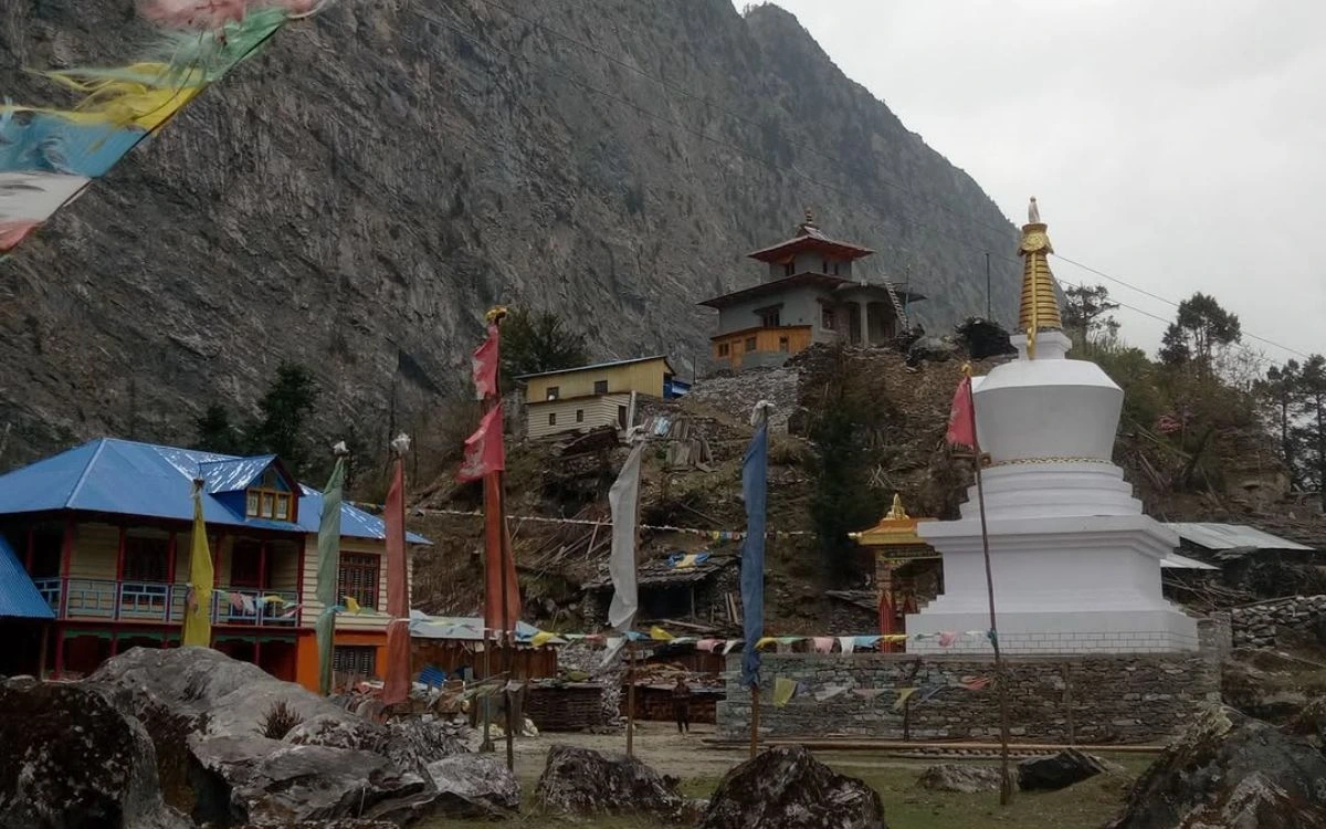 Buddhist monastery with white stupa and colorful prayer flags in Manaslu village