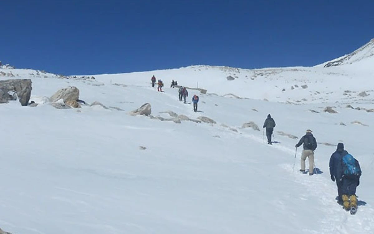 Trekkers ascending snow-covered trail toward Larkya La Pass in November