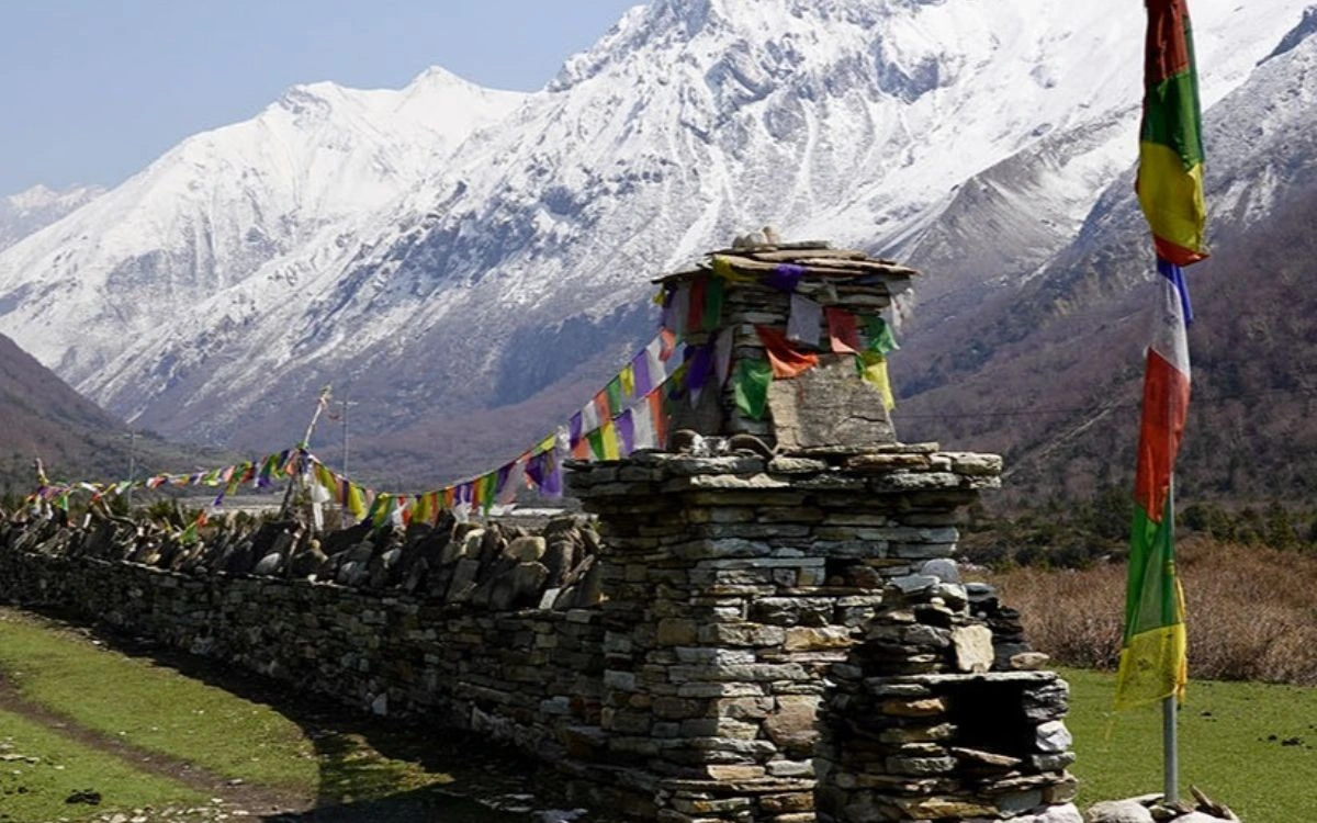 Stone mani wall with prayer flags and snow-covered mountains, Manaslu Circuit