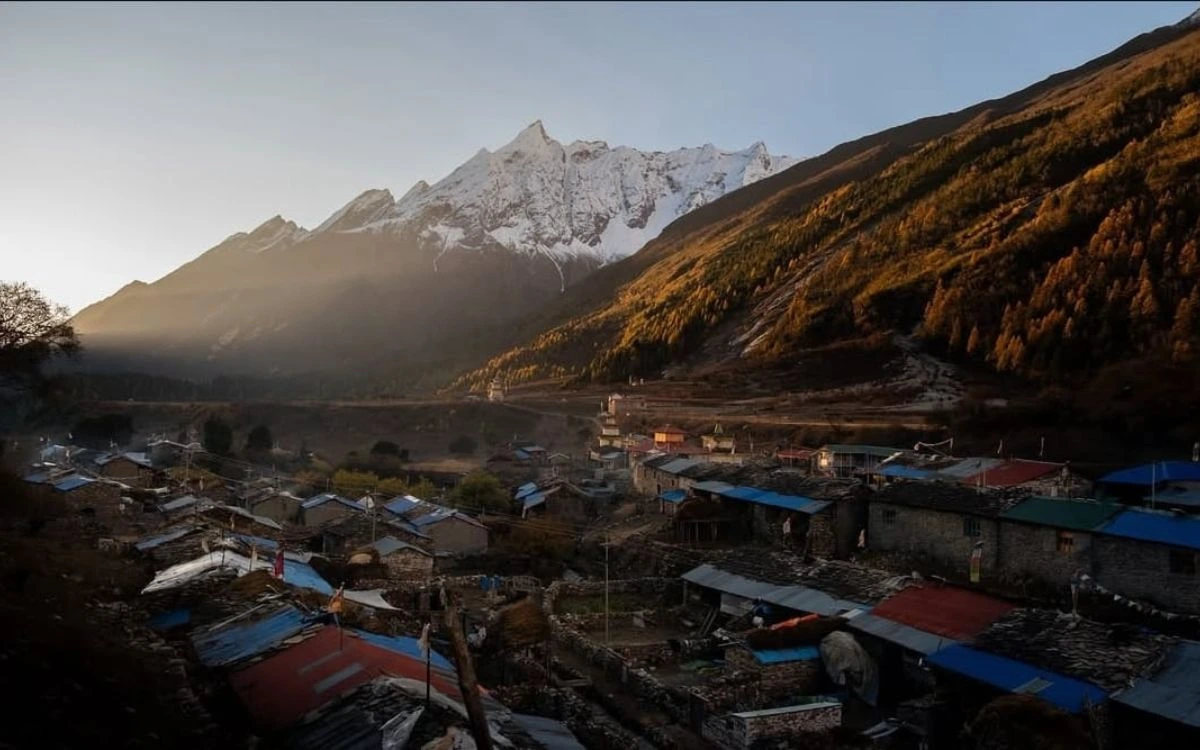 Traditional mountain village at sunrise with Himalayan peaks behind Manaslu Conservation Area