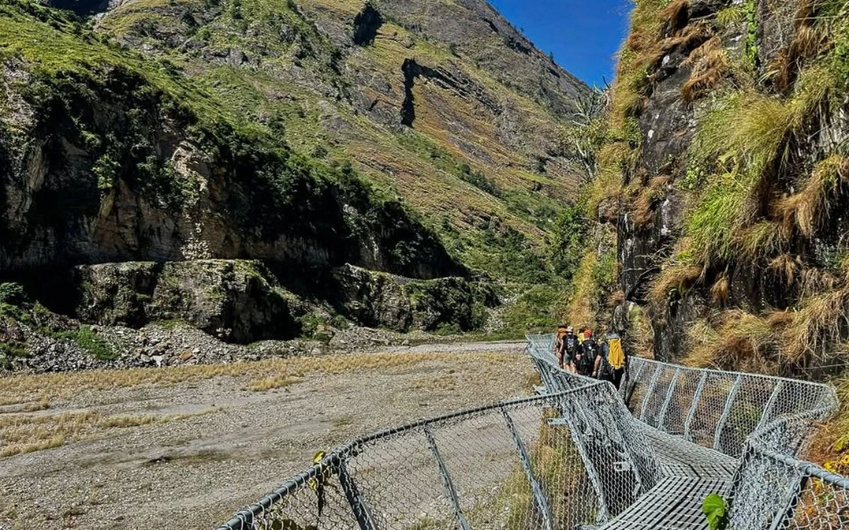 Trekkers crossing a suspension bridge along the Manaslu Circuit trail