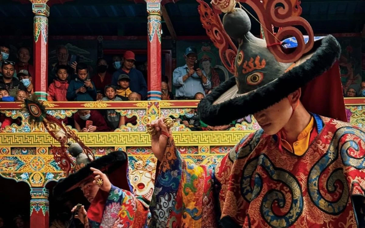 Dancing monk in brocade robes as spectators watch