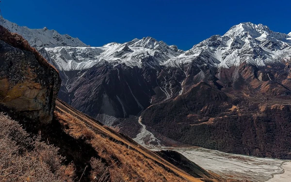 Snow-capped Himalayan peaks above a steep valley with a glacial river below