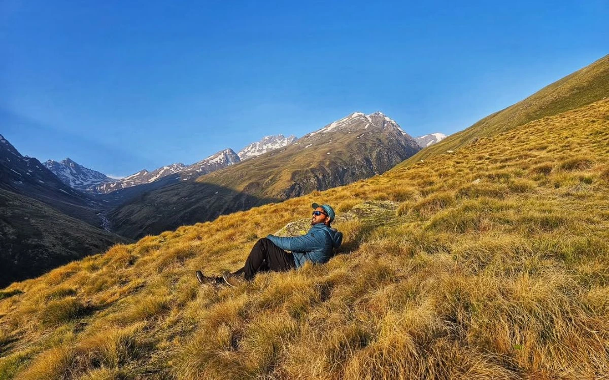 Hiker resting on golden autumn hillside with Himalayan mountains in background