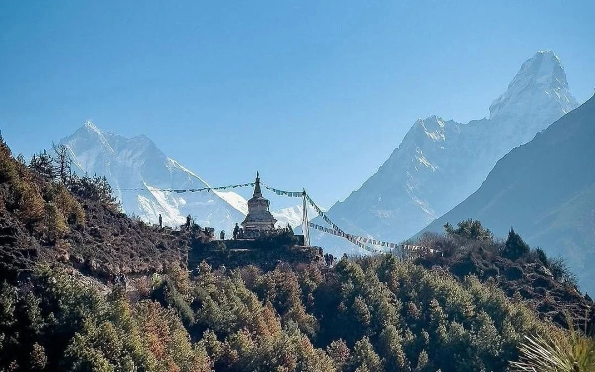 Buddhist stupa adorned with prayer flags framed by towering Himalayan peaks