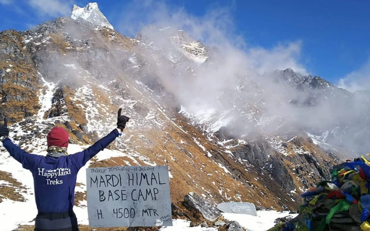 Trekker celebrating at Mardi Himal Base Camp sign at 4500m