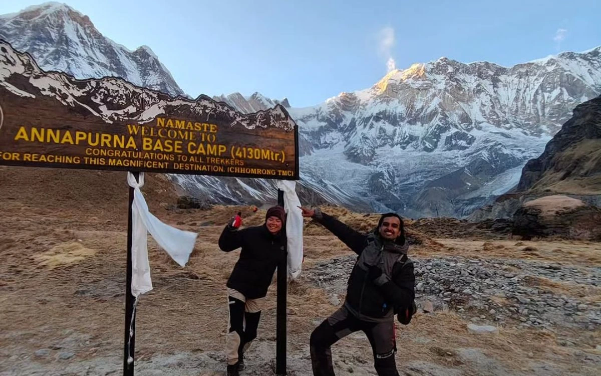Two trekkers posing at the Annapurna Base Camp welcome sign at 4130m