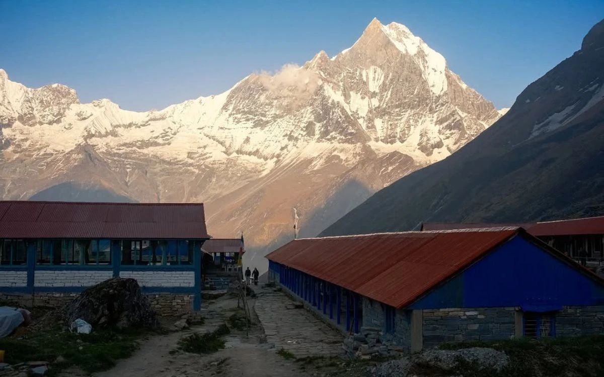 Machhapuchhre peak rising sharply above the blue and red teahouse lodges at Annapurna Base Camp