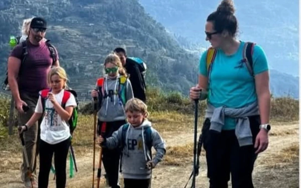 Family with kids hiking a mountain trail in Nepal with trekking poles