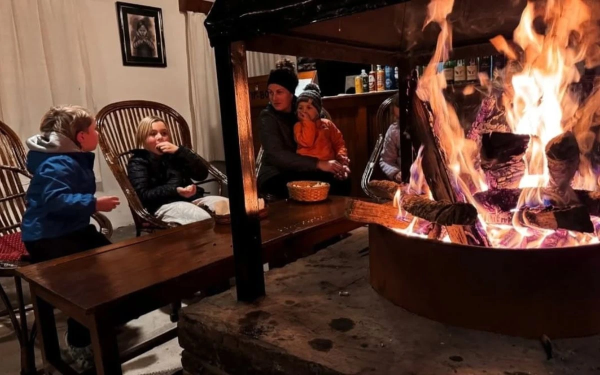 Family warming up by a fireside at a Nepal teahouse after trekking
