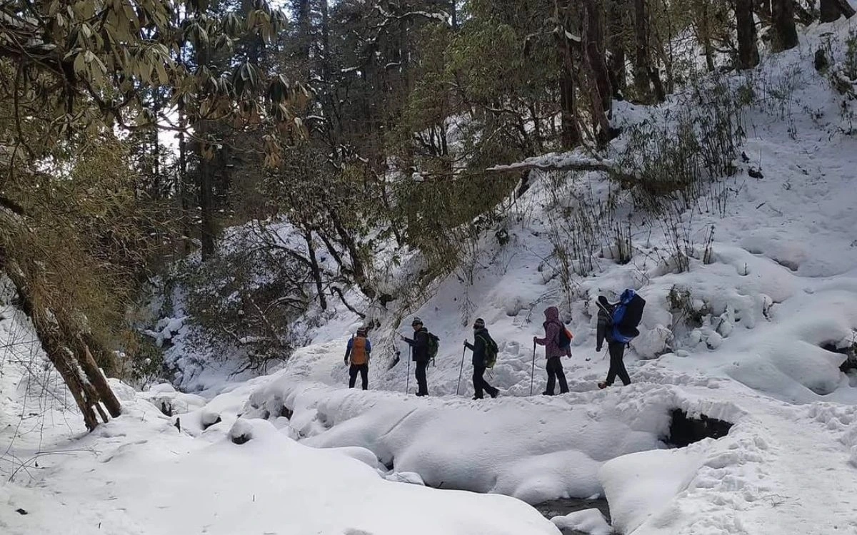 Trekkers crossing a snow-covered trail in Nepal in January