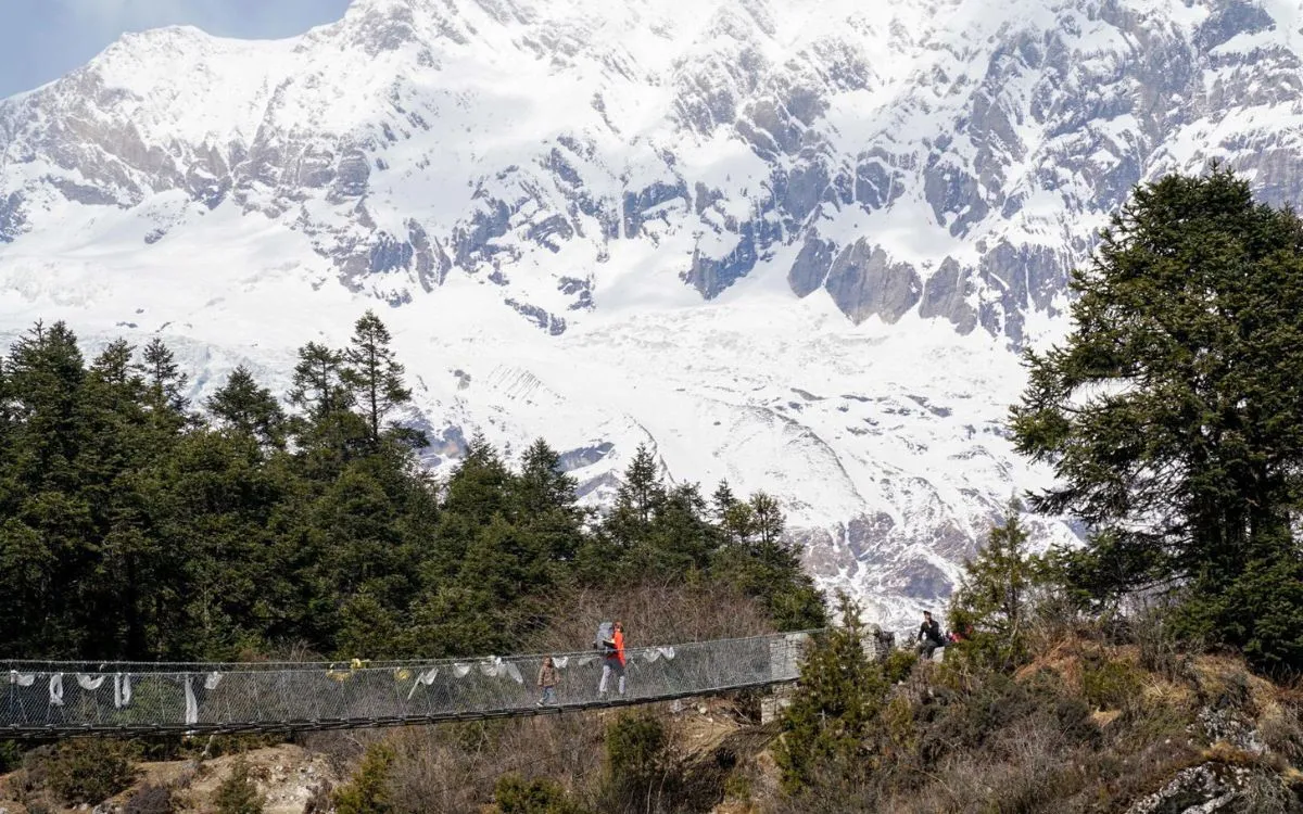 Solo trekker on snowy Manaslu trail with dramatic Himalayan peaks in background