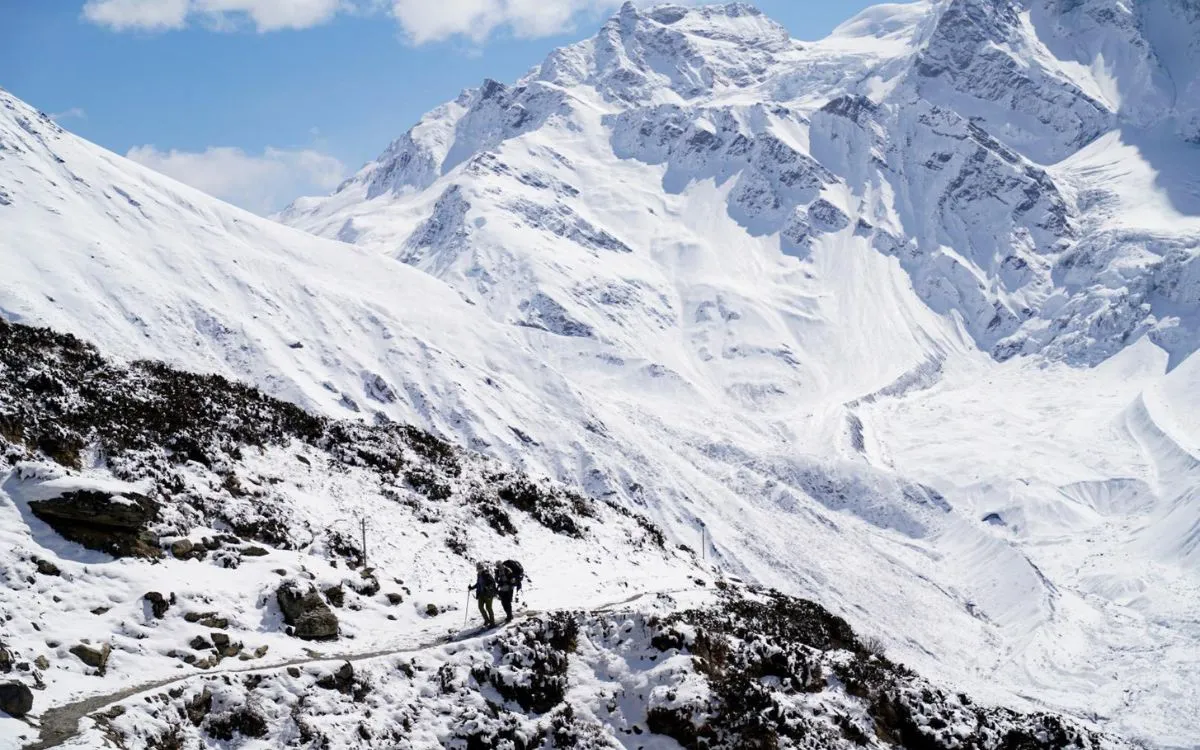Solo trekker on snowy Manaslu trail with dramatic Himalayan peaks in background