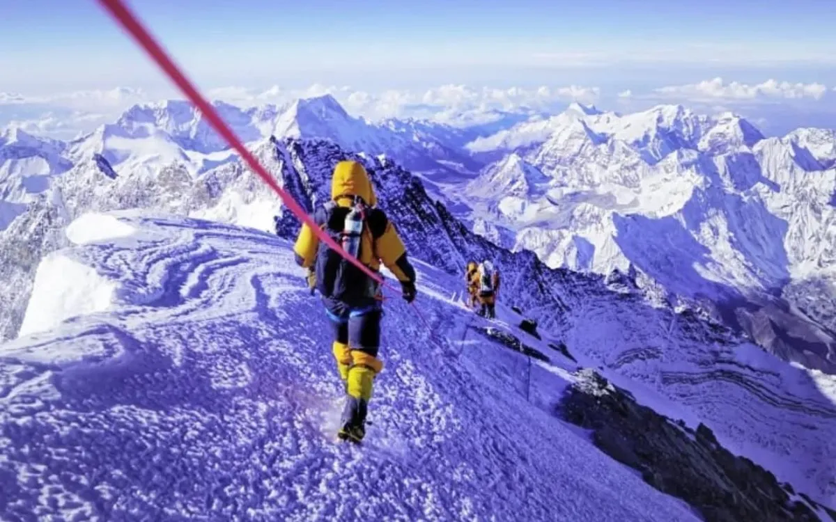 Climbers ascending Mount Everest's snowy ridge with rope assistance