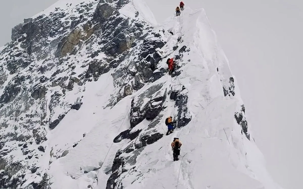 Mountaineers climbing Everest's steep snowy slope with safety ropes