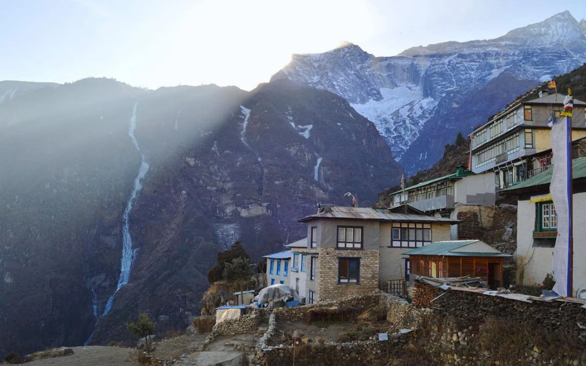 Stone teahouse lodges in Phakding at dusk with waterfall and mountain backdrop