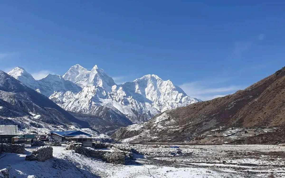 Pheriche village teahouses covered in snow with the dramatic Taboche and Cholatse peaks behind