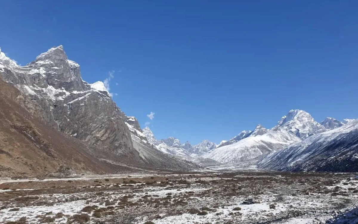 A wide snow-dusted high-altitude valley near Pheriche with jagged peaks on either side