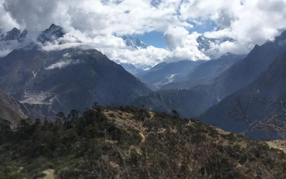 Panoramic valley view from near Phortse with Everest and Lhotse peeking through clouds in the far distance