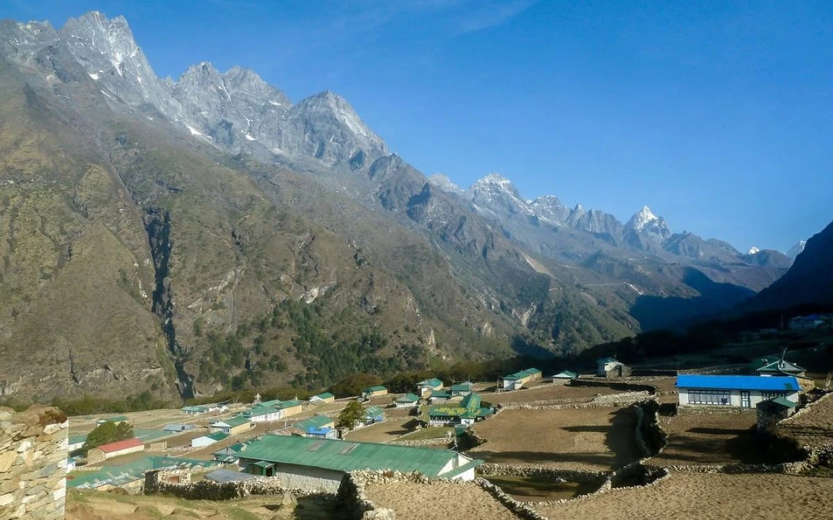 Overview of Phortse village's green-roofed houses and stone-walled fields nestled beneath a dramatic serrated ridgeline