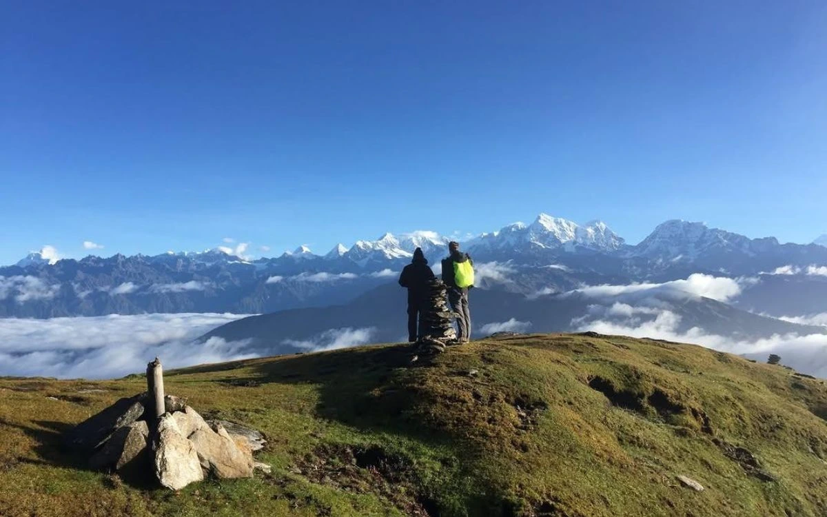 Trekkers at Pikey Peak summit viewing Everest and Himalayan range above clouds