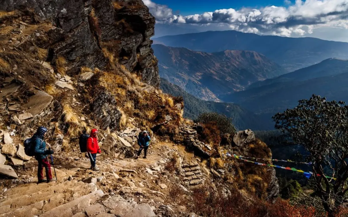 Rocky stone path with trekkers and mountain valley views