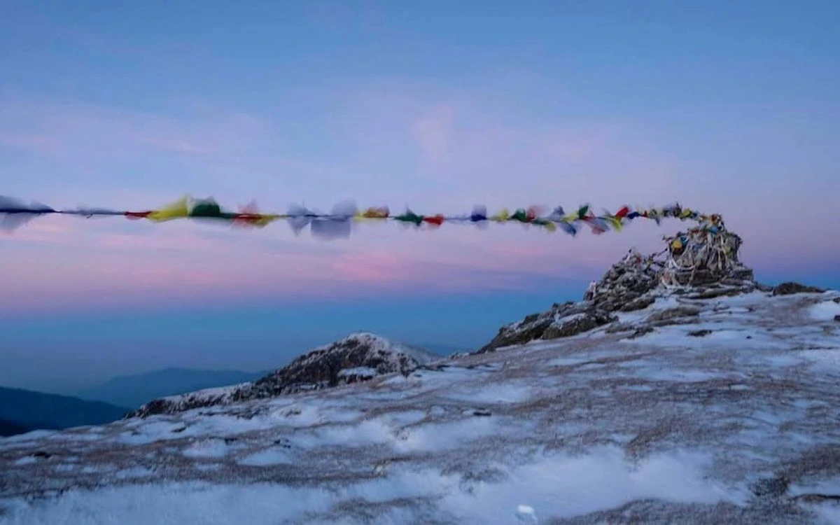 Prayer flags at snow-covered Pikey Peak summit at dawn