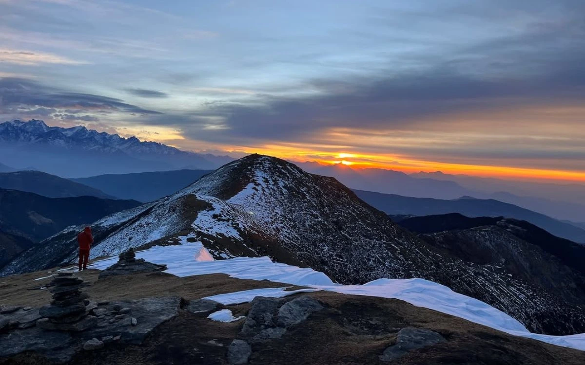 Trekker watching sunset over snowy Pikey Peak ridge with Himalayan panorama