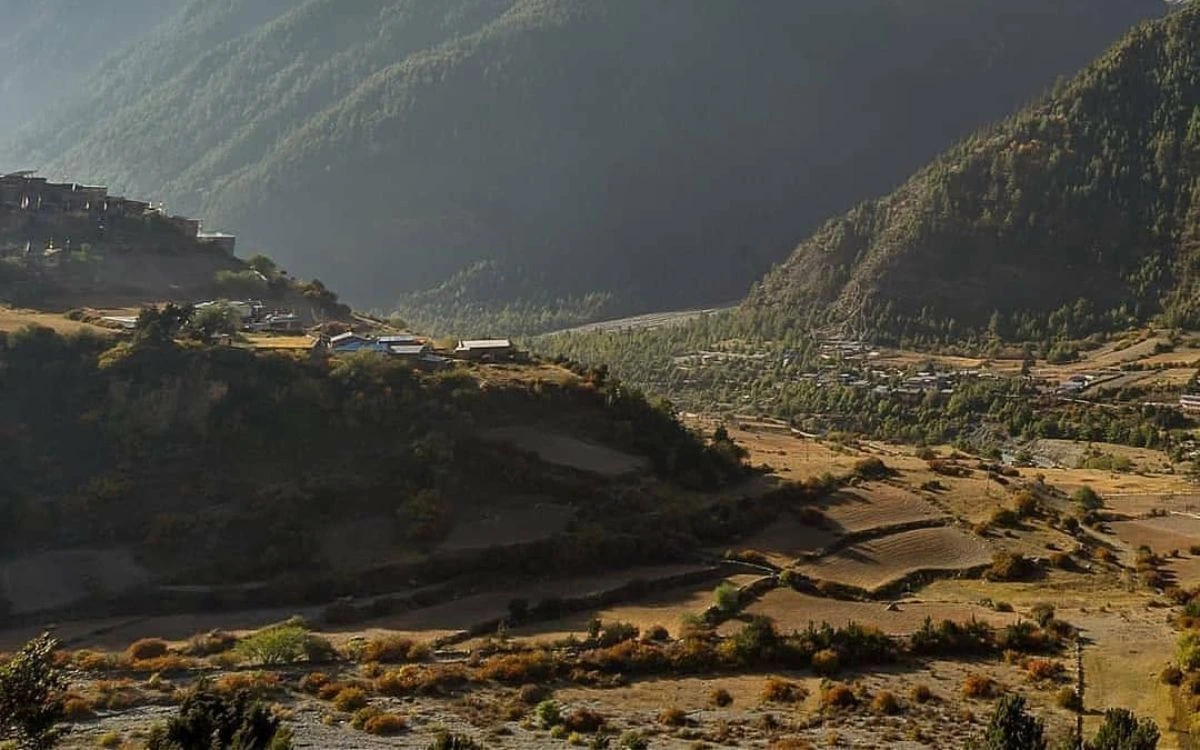 Golden-hour view of Upper and Lower Pisang villages in a valley flanked by forested Himalayan slopes