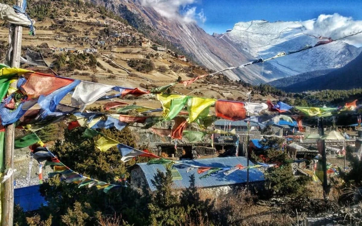 Colorful Tibetan prayer flags over Pisang village with snow-capped Annapurna peaks in the background