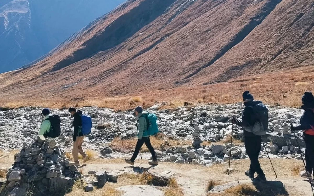 Trekking group using poles while crossing rocky terrain in high-altitude valley