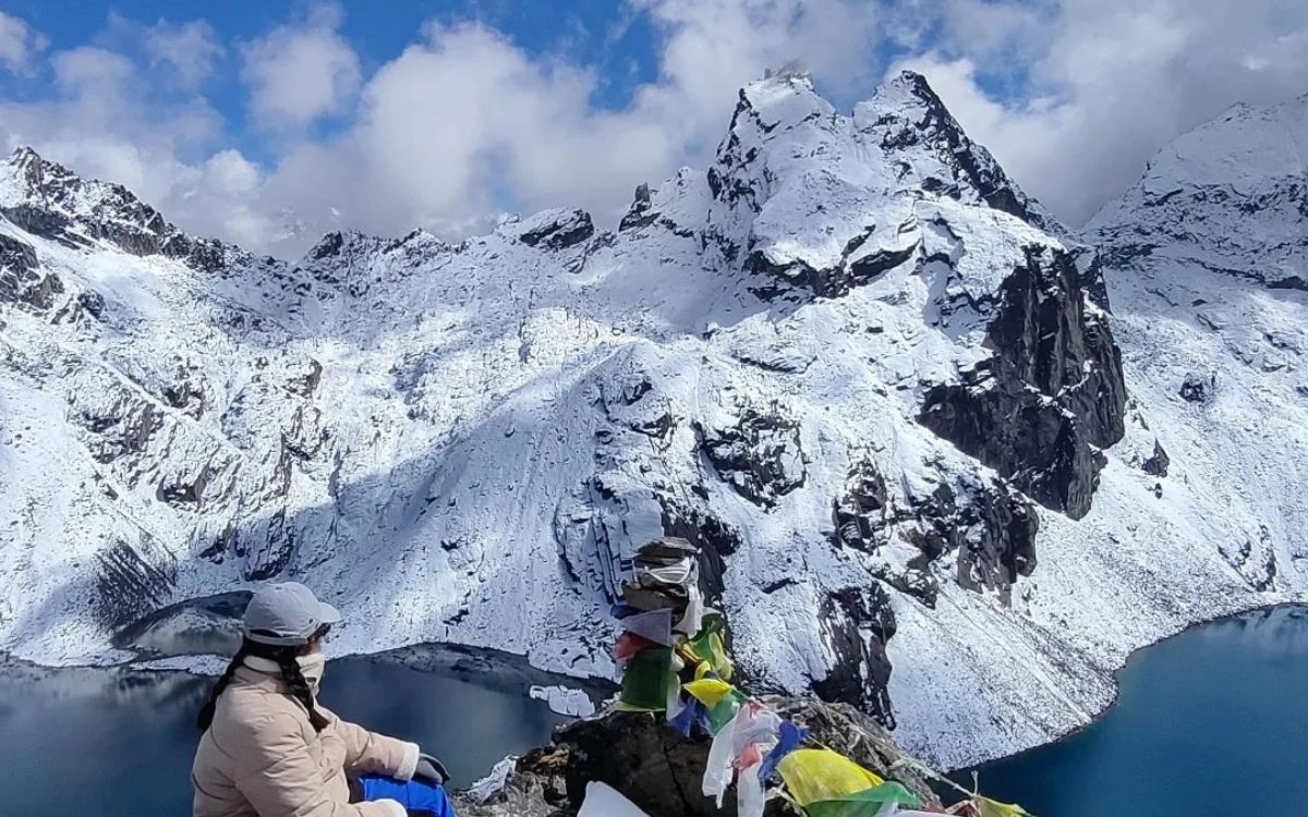 Trekkers resting at a mountain viewpoint overlooking snowy peaks and a glacial lake near Samdo