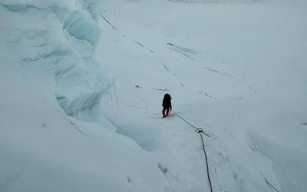 Mountaineer with rope climbing through blue ice crevasse in Khumbu Icefall on Everest climbing route